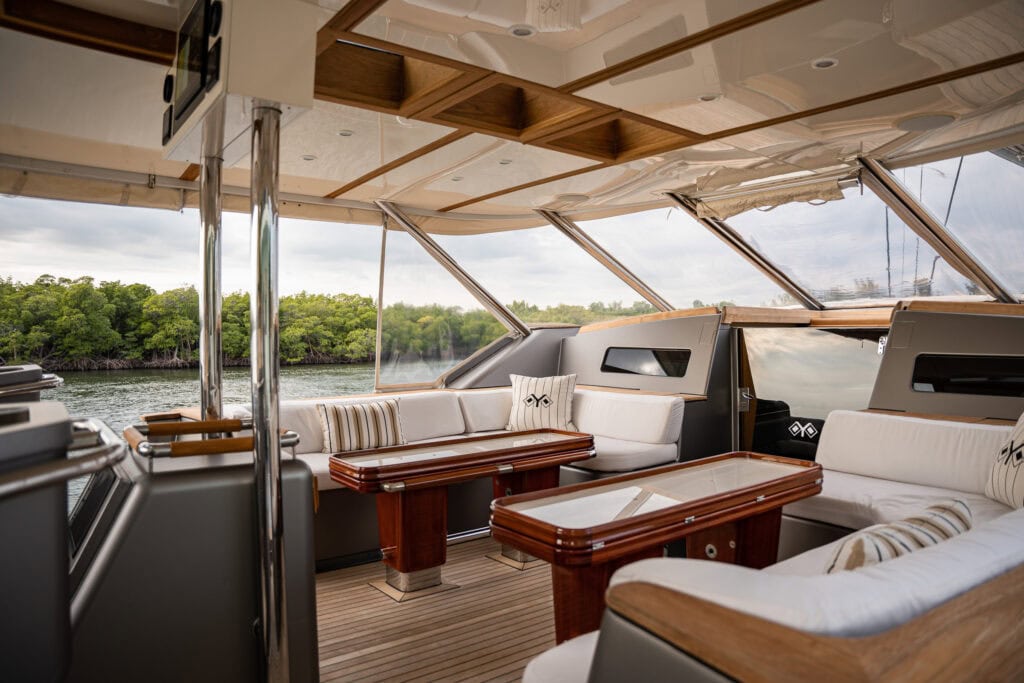 Yacht saloon interior with cream upholstery, polished wood table and panoramic windows