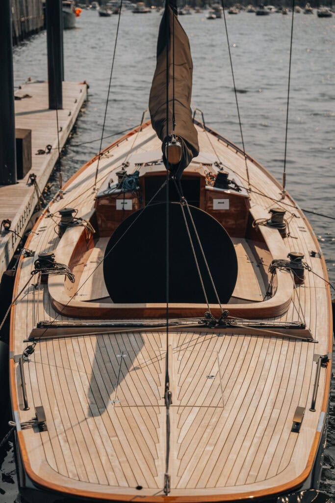 Varnished teak foredeck and deck hardware of a classic sailing yacht alongside