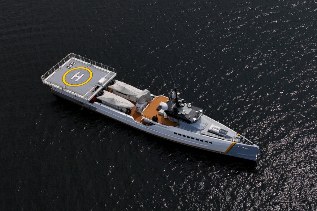 Overhead drone view of a grey explorer motor yacht with a helipad on the foredeck