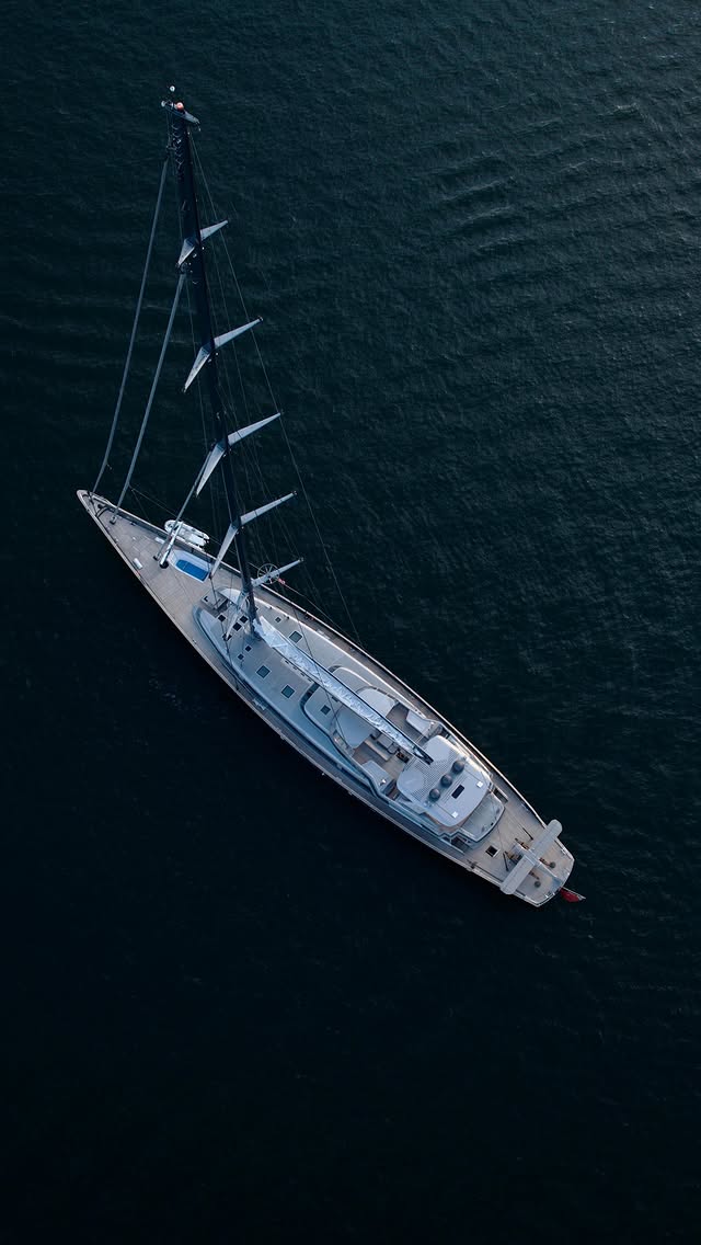Overhead drone view of a white sailing yacht on dark blue open water