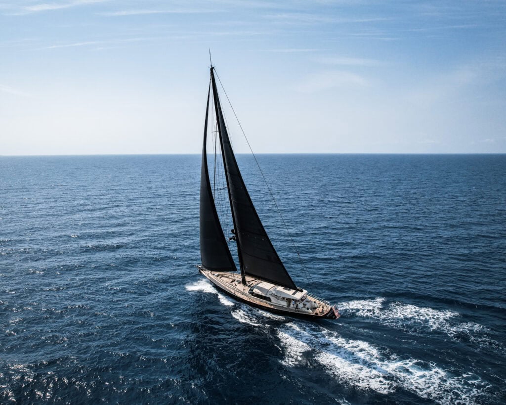 Aerial view of a blue-hulled sloop under sail offshore on a New England yacht delivery passage
