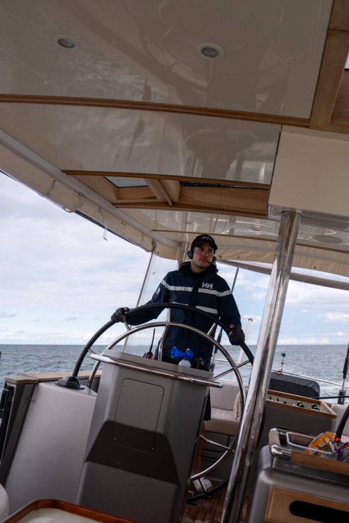 Captain Nicolas Escalante at the helm of a sailing yacht under way on a New England yacht delivery passage