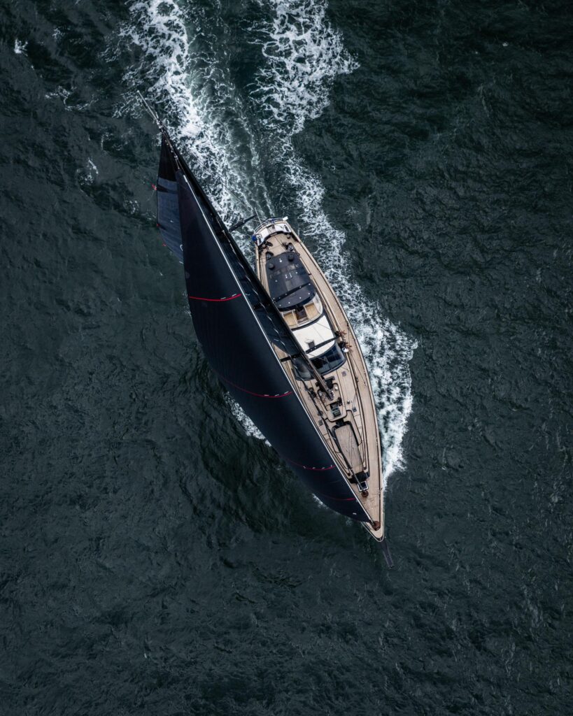 Overhead drone view of a classic yacht under way, wake trailing astern