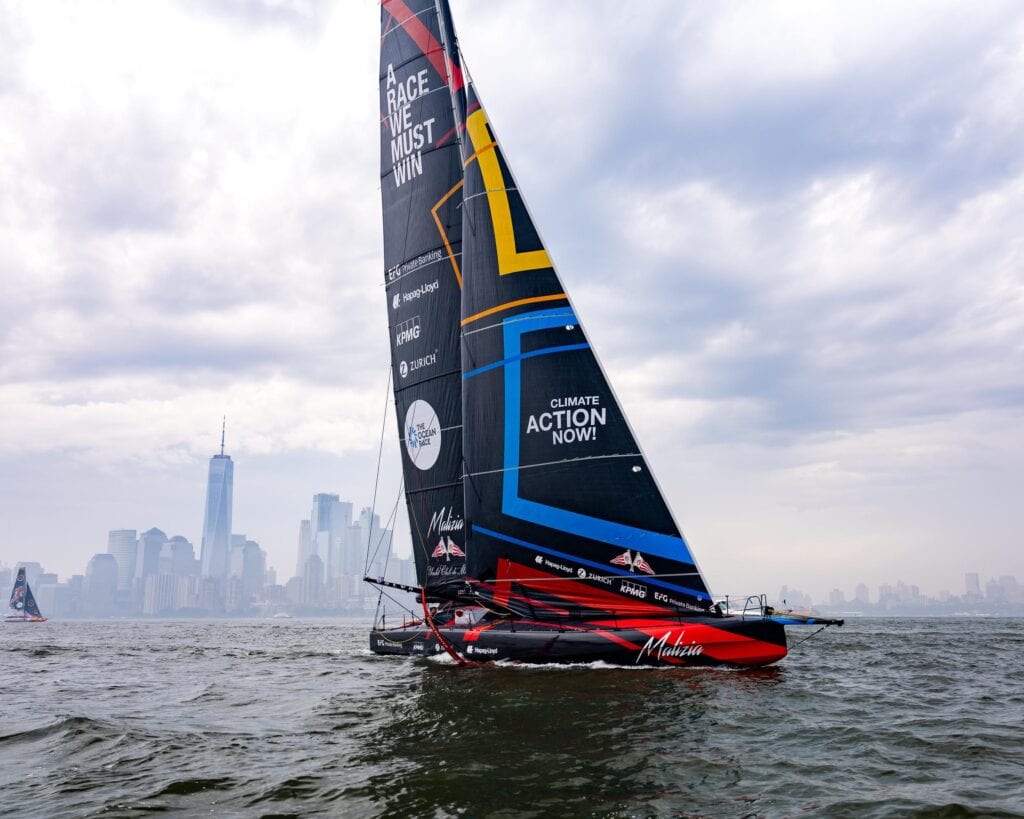 IMOCA 60 racing yacht under way against the Manhattan skyline, New York