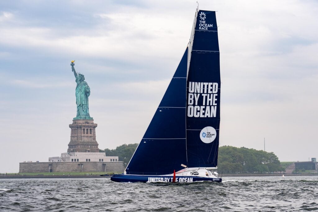 IMOCA 60 racing yacht passing the Statue of Liberty, New York