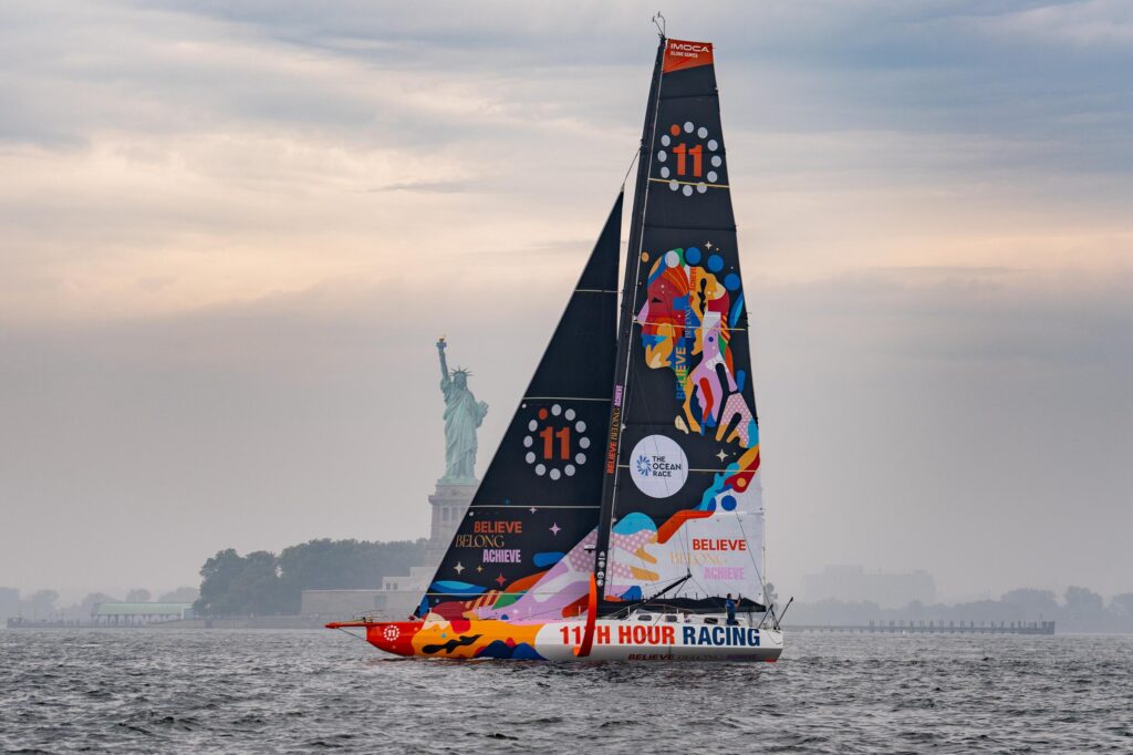 IMOCA 60 under way past the Statue of Liberty at the New York race start