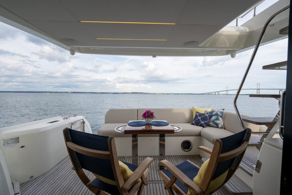 Shaded cockpit seating and dining table aboard At Eaze, Newport in the distance