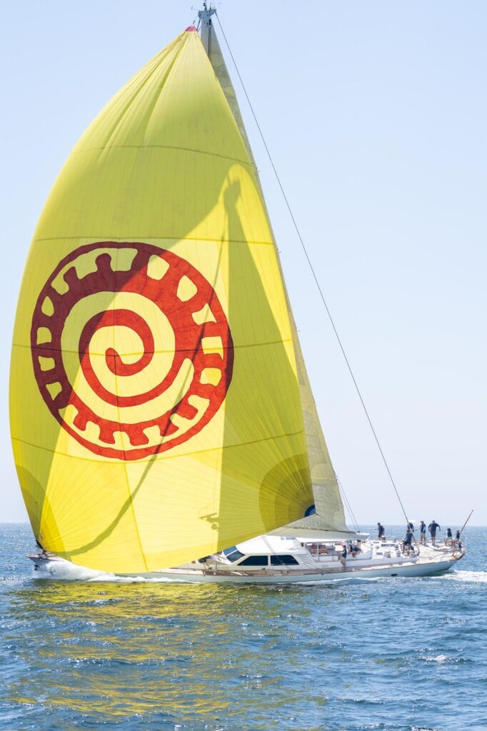 Yellow spinnaker carrying a red spiral emblem on race day, Newport