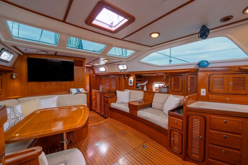 Saloon settee and dining table in varnished teak aboard the sailing yacht Rubycon